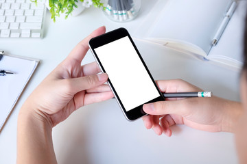 Mockup smartphone on hands working on office table with clipping path on display.