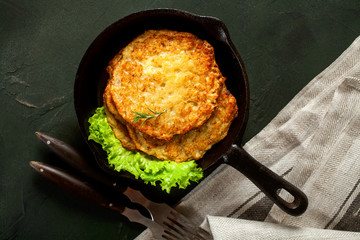 Potato hash brown with salad on a dark background. Latkes. The Jewish dish for a holiday Hanukkah. Top view - obrazy, fototapety, plakaty