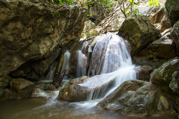 Little waterfall and big stone in big forest, stream on the way for hiking in jungle for making freshness and drink.