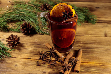 Christmas mulled wine with spices and fir tree branches and cones on wooden table