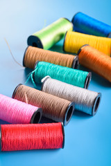 Colored thread coils on blue background, sewing, place for text