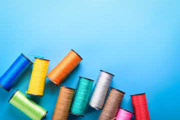 Colored thread coils on blue background, sewing, place for text