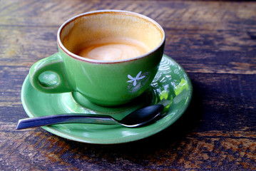 Close up green cup of hot coffee on the old wooden table
