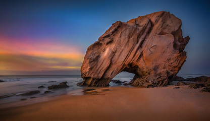 Fototapeta na wymiar Penedo do Guincho. 143'' long exposure of this peculiar rock formation at sunset with low tide, located in the Santa Cruz beach, Portugal