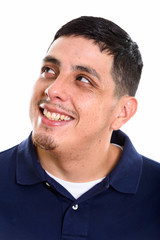 Face of young happy Hispanic man smiling while thinking and look