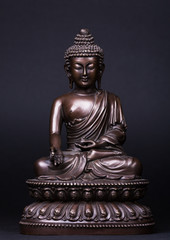 Buddha's figure, brown color made of metal in a meditation pose with the hands keep a pearl of knowledge.