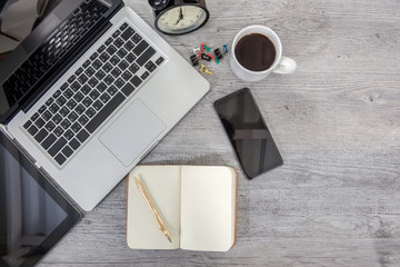 White office desk table with blank notebook, computer keyboard and other office supplies.
