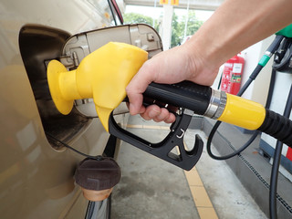 Hand holding petrol pump refuelling car