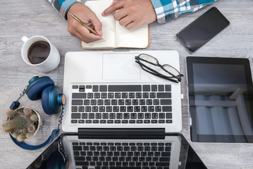 White office desk table with blank notebook, computer keyboard and other office supplies.