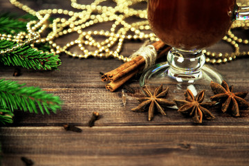 Mulled wine with spices and Christmas tree on wooden background