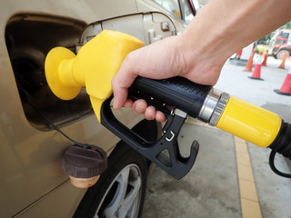 Hand holding petrol pump refuelling car