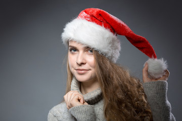 junge lächelnde Frau im grauen Pulli und Weihnachtsmütze