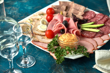 Cold smoked meat plate with prosciutto, salami, bacon, pork chops, cheese and olives on gray stone background.