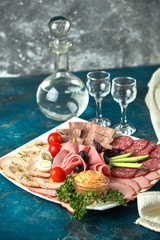 Cold smoked meat plate with prosciutto, salami, bacon, pork chops, cheese and olives on gray stone background.