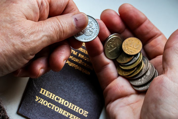 Woman's hands holding russian coins over the pension certificate. Russian translation - Ministry of Social Protection of Population of Russian Federation. Pension Certificate.