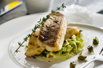 Fillet of halibut on a pillow of stewed leeks on the white plate.