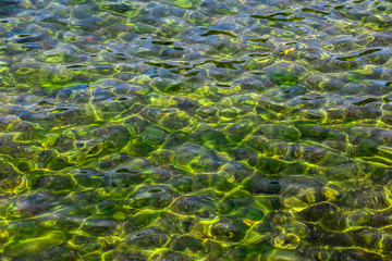 Surface of transparent, clear, beautiful colorfull water. Reflection and refraction of light in water. Abstract natural sea water background.