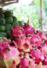 Colourful display of pink dragonfruit also called Pitaya, green mangoes and papayas on a fruit...