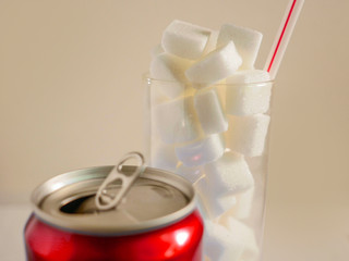conceptual still life image of glass with straw full sugar cubes and soda refresh drink  in...