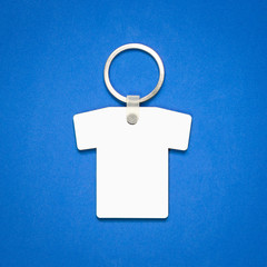 White key ring on blue background. Key chain for your design. Hanging accessory or souvenir. ( Shirt shape )