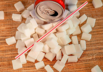 conceptual still life image of pile of sugar cubes and soda refresh drink with straw in unhealthy...