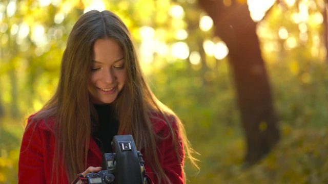 Beautiful girl with a camera walks through the autumn forest and takes pictures. Weekend outside the city