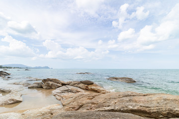 Fototapeta na wymiar rocks on the beach with cloudy blue sky