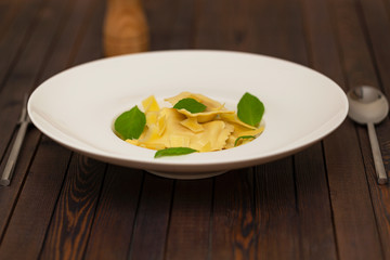 Plate of ravioli with basil on dark background