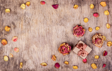 Gift box, dry roses and wooden background.  Dry flowers, dried roses. Copy space.