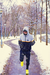 Fototapeta na wymiar Man jogging in snowy park and cold weather.