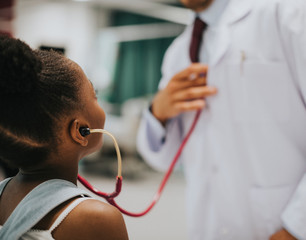 Friendly pediatrician entertaining his little patient