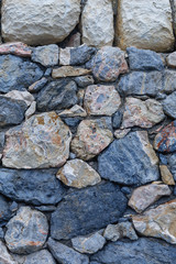 beautiful stone wall of stones of different colors and sizes closeup, vertical
