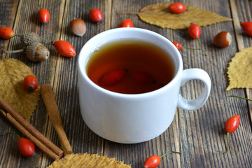 Autumn composition with rose hips nuts leaves a Cup of tea. A Cup of tea with rose hips. Autumn hot drink