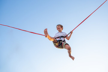 Smilling excited boy jumping on a trampoline with insurance.