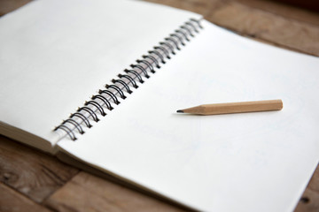 Pencil on empty notebook on wooden table