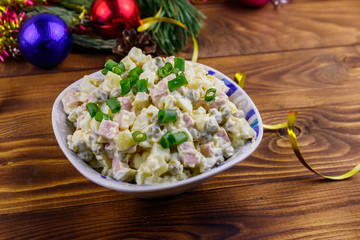 Traditional Russian festive salad Olivier and New Years decorations on wooden table