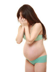 両手で顔を覆う緑色の下着を着た臨月の妊婦