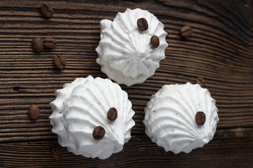 Sweet dessert - vanilla marshmallow (zephyr) on a wooden table with coffee beans, selective focus.