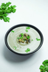 Mushroom cream soup with parsley in a black bowl
