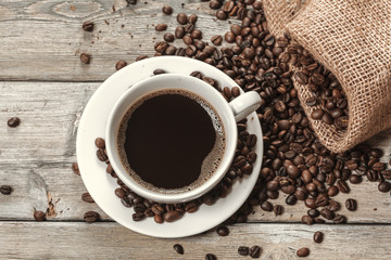 Cup of coffee with beans on table