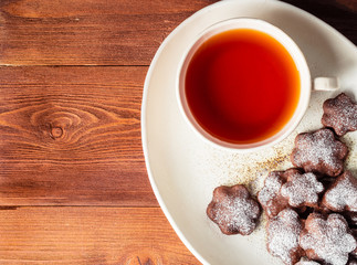 Winter holiday composition, top view, copy space, brown wooden background. Tea, flax cookies with cinnamon