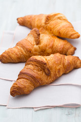 Tasty buttery croissants on old wooden table.