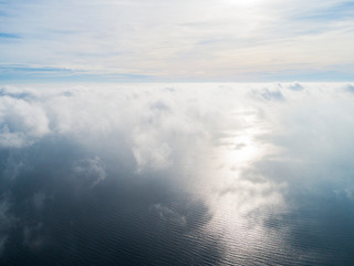 Fototapeta premium Aerial view White clouds in blue sky. Top view. View from drone. Aerial bird's eye view. Aerial top view cloudscape. Texture of clouds. View from above. Sunrise over the sea
