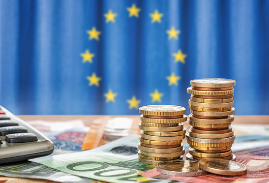 Geldscheine und Münzen vor der Flagge der Europäischen Union