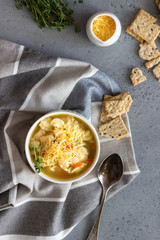Two white bowls of Italian soup minestrone with pasta and white beans topped with fresh thyme and served with crackers on grey concrete background. Vegetarian food concept.