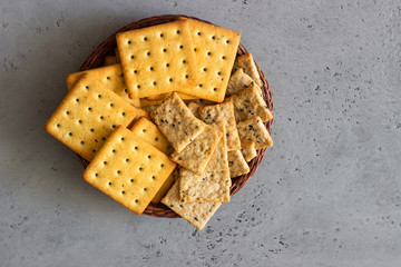 Thin crispy salted crackers with seeds and herbs on grey concrete background. 