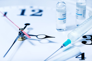 Vaccination time. Vaccine in vial with syringe on clock background. Prevention immunization illness.