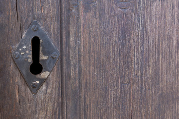 Old former keyhole on wooden background with copy space.Closeup of a vintage rusty one.Concept of spying