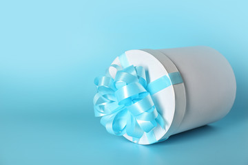 Gift box with blue ribbon on color background