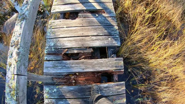 Stepping over broken boards of wooden bridge